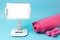 Tablet sports mat and pink dumbbells on blue background, concept workouts at home