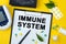 Tablet with text IMMUNE SYSTEM. Nearby is a tonometer, medicines, vitamins and a pen