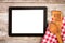 Tablet on wooden surface and serving spoons.