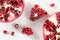 Tabletop closeup view - pomegranate half, clusters of gem like fruits scattered on white board