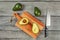 Tabletop view, avocado cut in half, seed visible, on a chopping