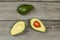 Tabletop view, avocado cut in half, whole pear above, placed on