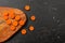 Tabletop view, carrot sliced to small circles on a chopping board, some on black marble next