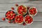 Tabletop view - five small bowls with strawberries, some of them spilled on gray wood desk