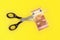 Tabletop view - large scissors cutting ten eur banknote over yellow board. Cut fees concept