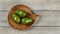 Tabletop view, three avocado pears on wooden carved bowl
