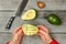 Tabletop view, woman hands holding avocado with cuts, preparing