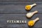 Tablets and capsules in wooden spoons with the inscription Vitamins on a wooden background. Copy space. Vitamins, prebiotics, prob