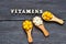 Tablets and capsules in wooden spoons with the inscription Vitamins on a wooden background. Copy space. Vitamins, prebiotics, prob