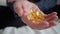 Tablets of vitamins with fish oil, omega, amino acids in the hand. Elderly man holds tablets with vitamin. Woman in her