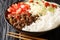 Taco rice takoraisu is a Mexican Japanese fusion dish consisting of seasoned ground beef, shredded lettuce, and chopped tomatoes