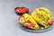 Taco shells on stone plate, with lettuce, ground beef meat,  mashed avocado, tomato, red onion and jalapeno pepper, horizontal,