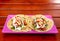 Tacos. Handmade Mexican food served in a pink plate placed on a wooden surface. Authentic Spicy Food