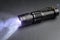 Tactical waterproof flashlight. LED flashlight shines on the table in smoke