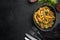 Tagliatelle with chanterelles and stewed rabbit, in bowl, on black stone background, top view flat lay, with copy space for text