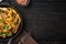 Tagliatelle with chanterelles and stewed rabbit, in frying cast iron pan or pot, on black wooden table , top view flat lay, with