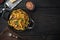 Tagliatelle with chanterelles and stewed rabbit, in frying cast iron pan or pot, on black wooden table , top view flat lay, with