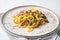 Tagliatelle with chanterelles and stewed rabbit, on plate, on white stone  background