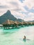 Tahiti Bora Bora beach vacation luxury hotel resort in French Polynesia. Woman paddleboarding doing watersport leisure