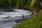 Tahitian surfer on a black sand beach.