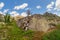 Taiga summer landscape. Huge granite boulder on a rocky mountain slope. Green lichens cover the stones. A sunny day on a mountain