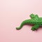 Tail of green crocodile toy on pastel pink background. Minimal art concept