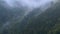 Taillaps steep mountain slopes covered with eternally green forest and powdered with snow on which low clouds flow. 4K