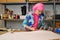 Tailor with pink hair and colorfull clothes cutting sewing patterns.