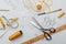 Tailor`s tools laid out on a table, scissors and a centimeter, sketches and threads in yellow and white. sewing workspace