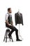 Tailor sitting on a chair next to a mannequin torso with a black suit