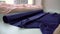 Tailor unrolling blue satin fabric on table in fashion atelier