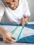 A tailor uses a measuring tape during his work in home workshop. A self-taught seamster in white t-shirt and glasses works with