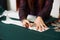 Tailor worktable in studio. Female hands making chalk markings of paper patterns on green fabric.