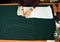 Tailor worktable in studio. Female hands making chalk markings of paper patterns on green fabric.