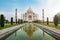 Taj Mahal front view reflected on the reflection pool, an ivory-white marble mausoleum on the south bank of the Yamuna river in Ag