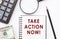 Take action now. Motivation text written on notebook with calculator, magnifier, dollar bills and pen