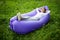 Take a break. Pretty young woman lying on inflatable sofa lamzac while resting on grass in park on the sun