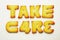 Take care word from alphabet biscuits on white background