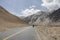 Take a low-angle photograph of a newly built straight asphalt road leading to the foot of a distant mountain