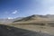 Take a low-angle photograph of a newly built straight asphalt road leading to the foot of a distant mountain