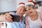 Take the picture already. Shot of an elderly couple taking a festive selfie at home.