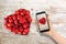 Take a picture with smartphone of heart shaped strawberries on wooden table