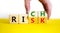 Take a risk and getting rich symbol. Businessman turns wooden cubes and changes the word `risk` to `rich`. Beautiful yellow ta