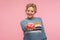 Take sweet donut! Portrait of happy adult woman with short hair in sweater giving doughnut to camera and smiling