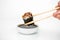 Take an unagi maki rolls with bamboo chopsticks and put it into soy sauce on white background, asian food, japanese cuisine