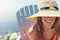 Take your hat wherever you go. a cheerful young woman wearing a hat while being seated on a chair next to a lake outside