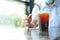 Takeaway cup of iced black coffee on table, blurred background a man hand reach out to coffee cup
