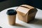 Takeaway duo Kraft paper box with hinged lid and cylindrical cup with black lid