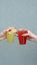 Takeaway glasses of summer drinks with ice in woman hands on grey background