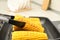 Taking corn from grill pan with tongs in kitchen